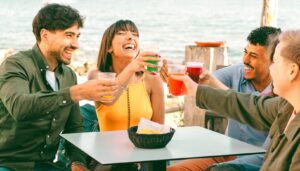 happy friends with drinks at coastal bar